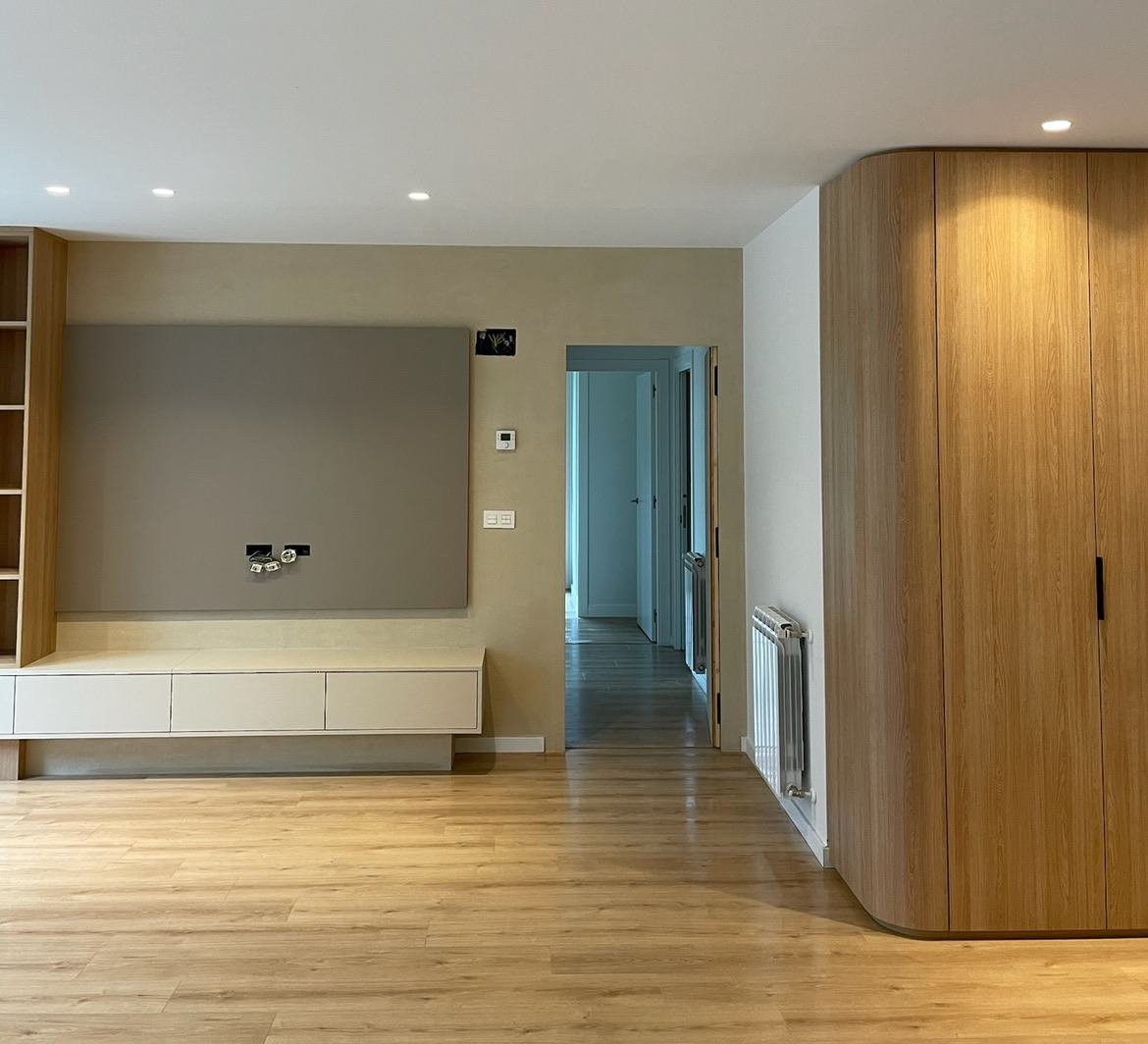 Salón con mueble de televisión y armario de madera redondeado